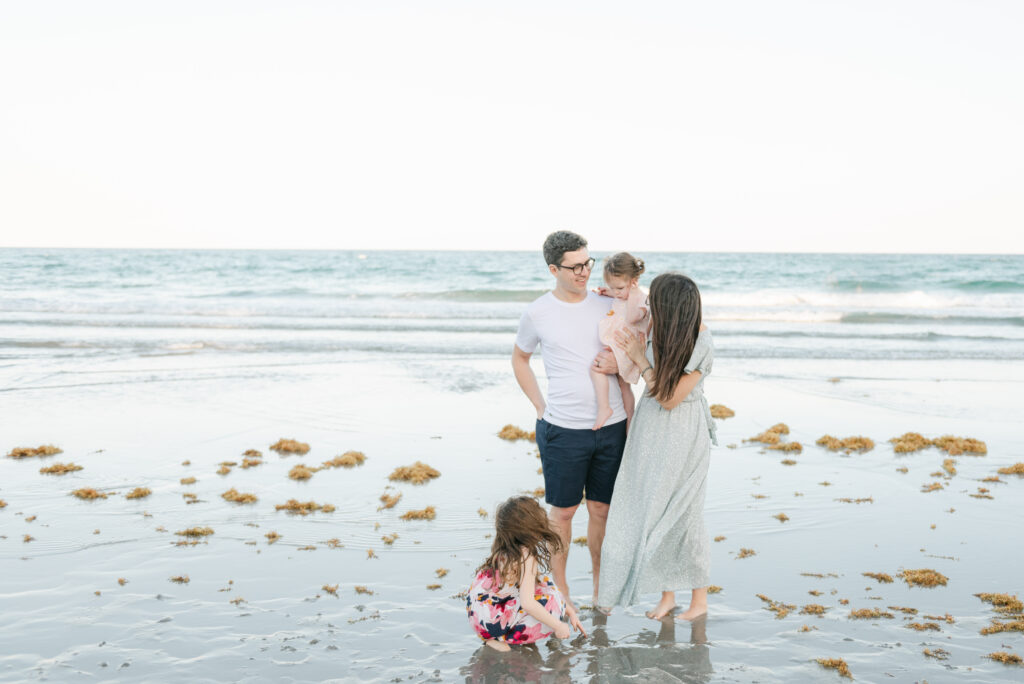 Family of four standing by the edge of the ocean