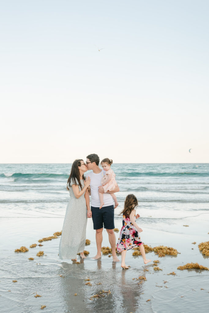 Mom and dad kissing, while daughter runs around