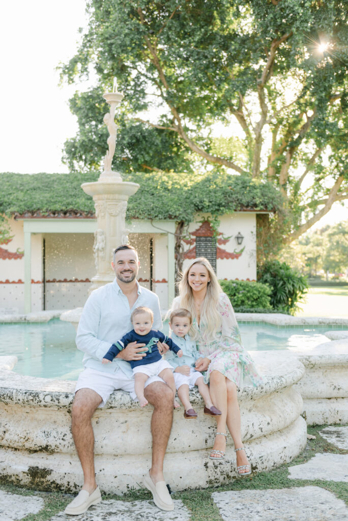 Mom, dad and sons sitting on side of fountain