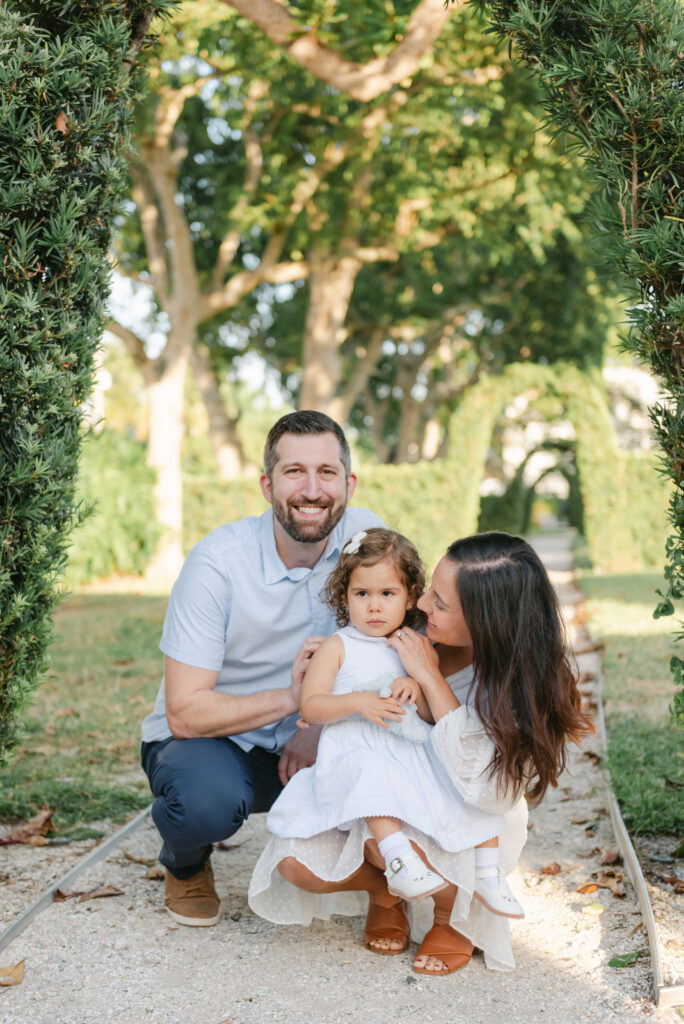 Mom, dad and little girl crouching down and smiling