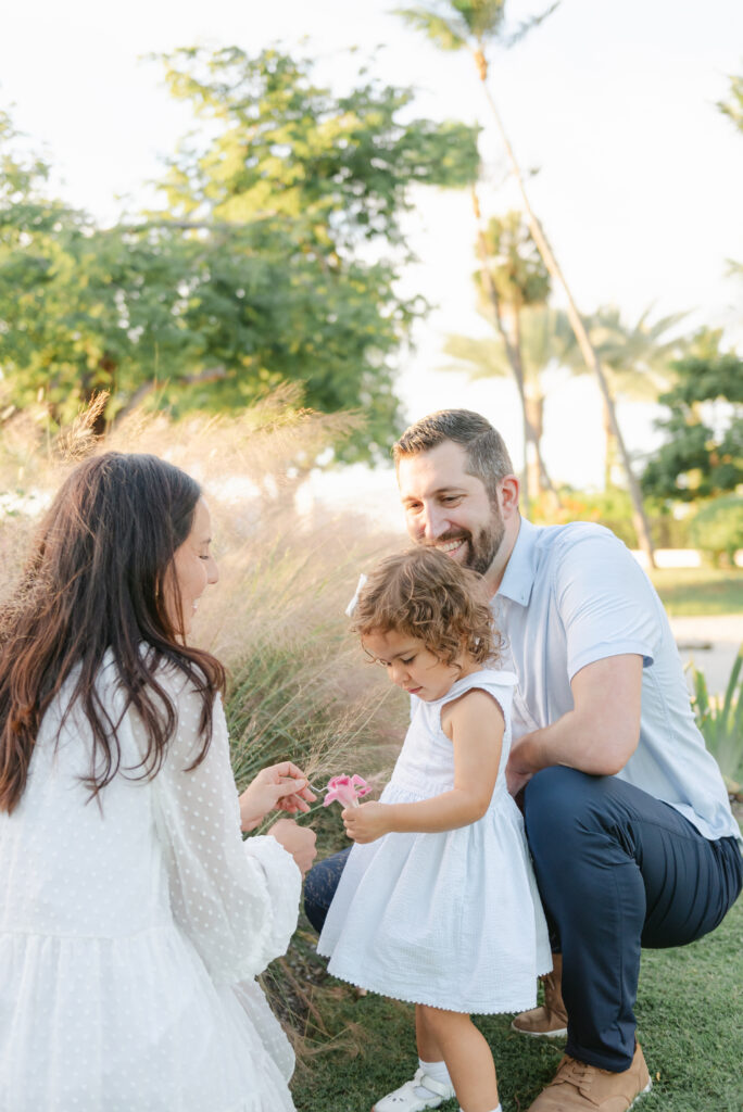 Daughter picking flowers, mom and dad looking on 