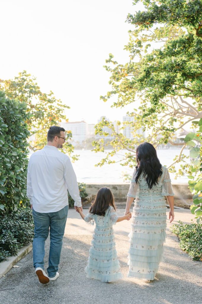 Mom, dad and daughter walking towards water holding hands