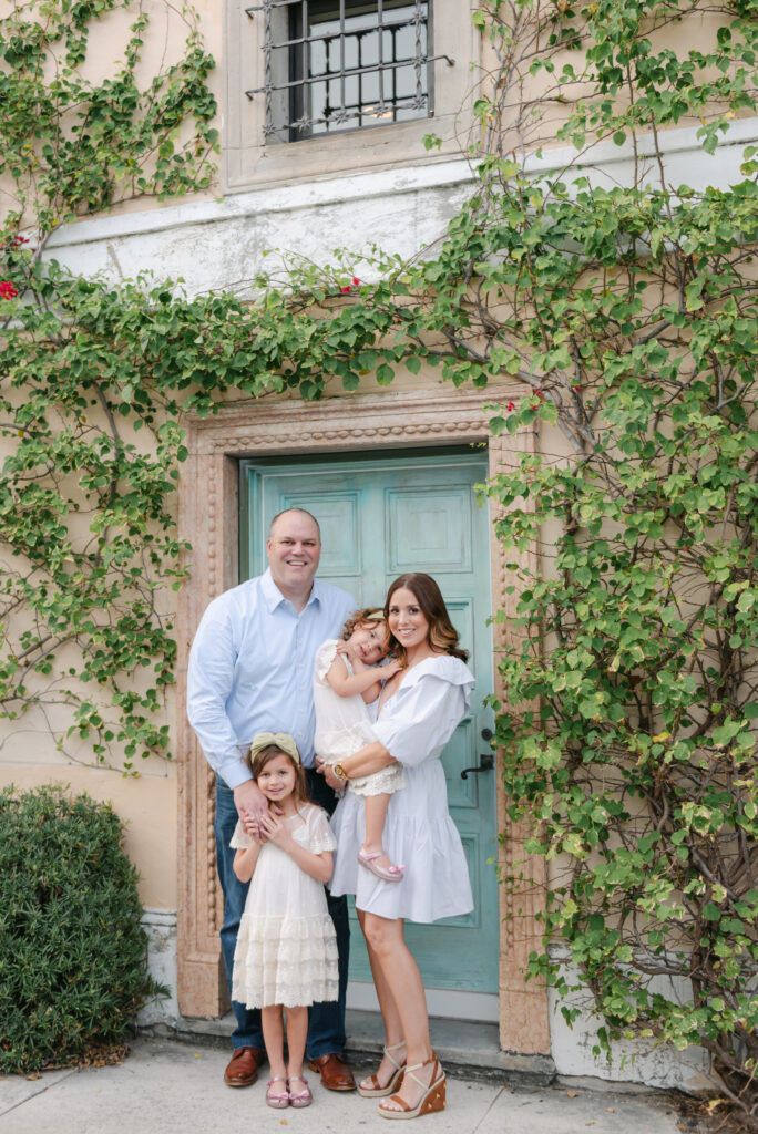 Mom, Dad and two daughters standing in front of teal door