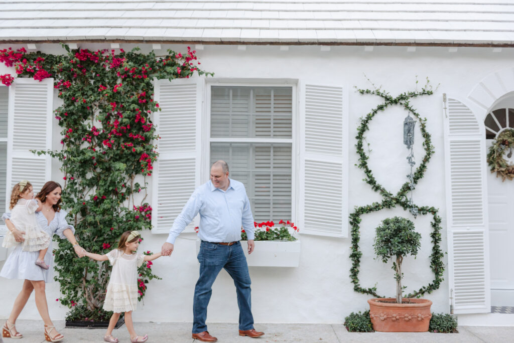 Family holding hands, walking in front of flowers and building