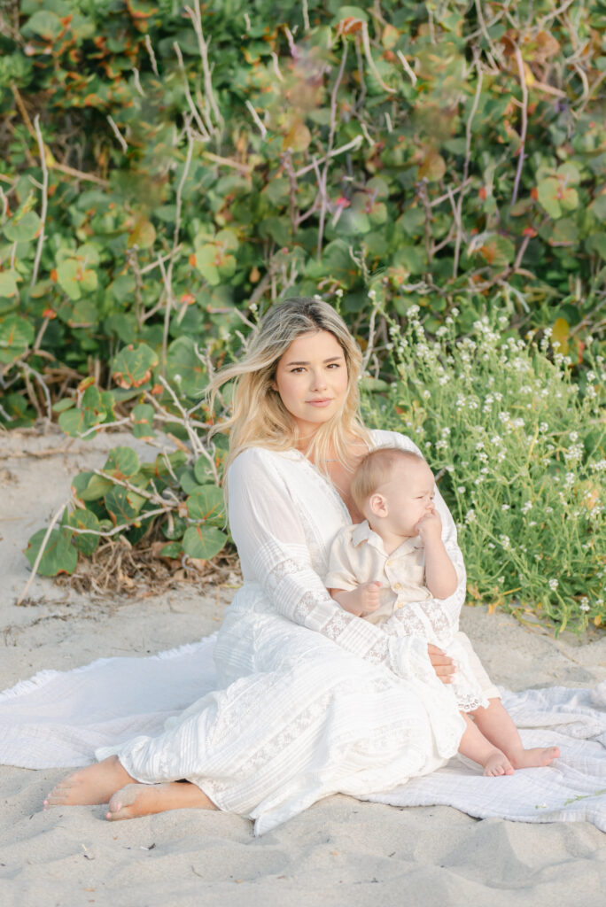 Mom sitting in front of greenery, holding son